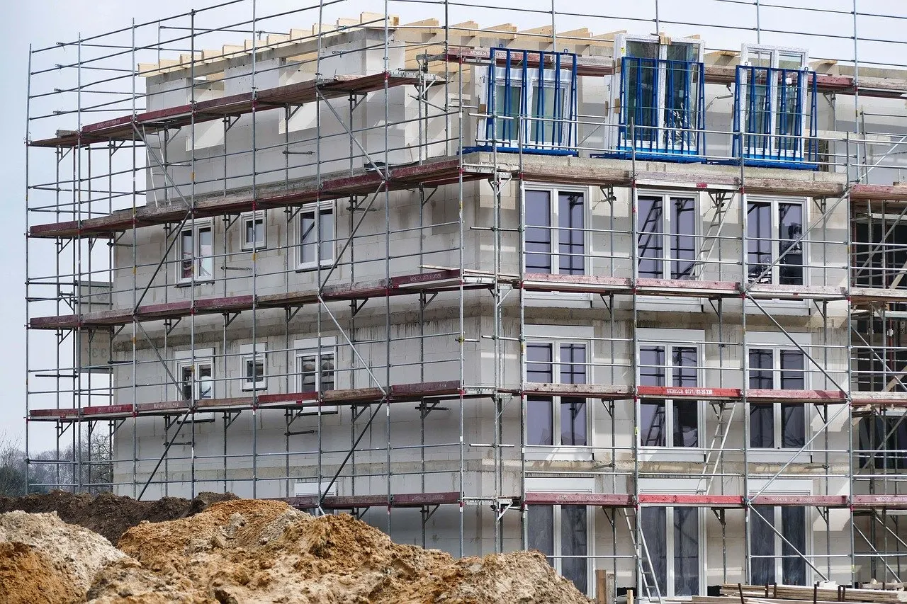 Neubau eines mehrgeschossigen Wohngebäudes, eingerüstet, mit Erdhaufen davor.