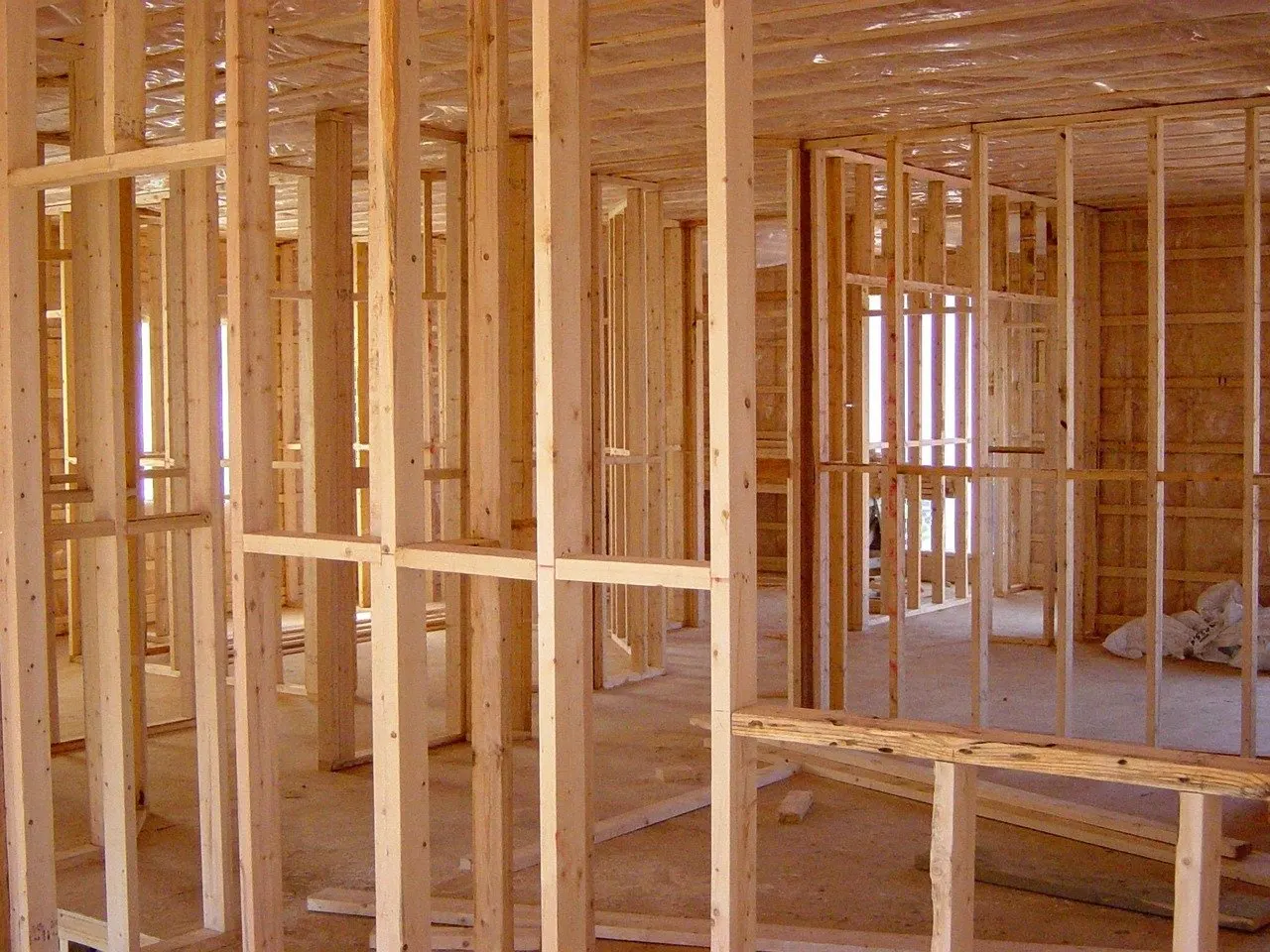 Rohbau eines Holzhauses mit sichtbaren Holzständern und Dachbalken im Innenraum