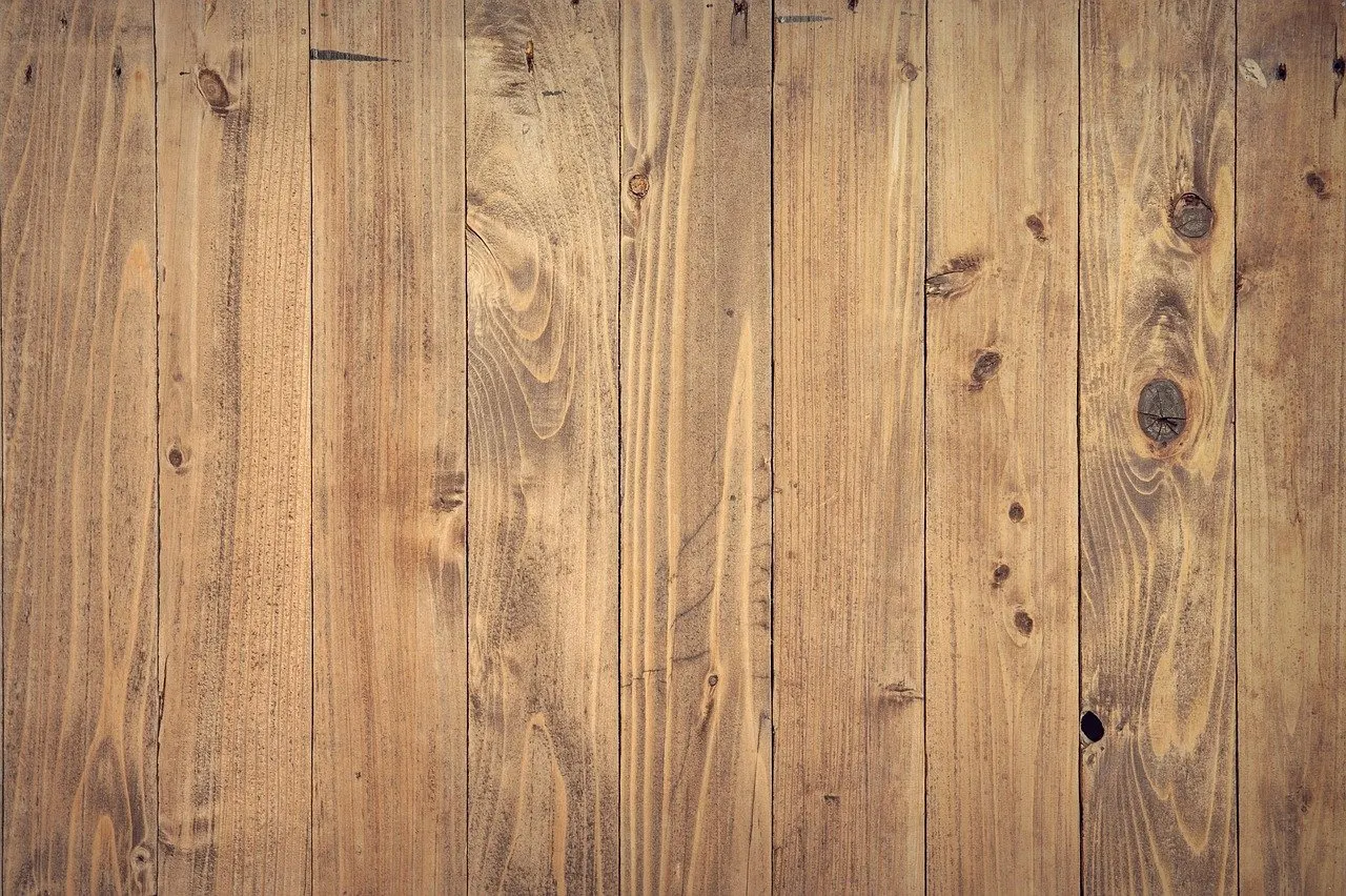 Nahaufnahme einer Wand aus vertikal verlegten, gebeizten Holzbrettern mit Astlöchern.