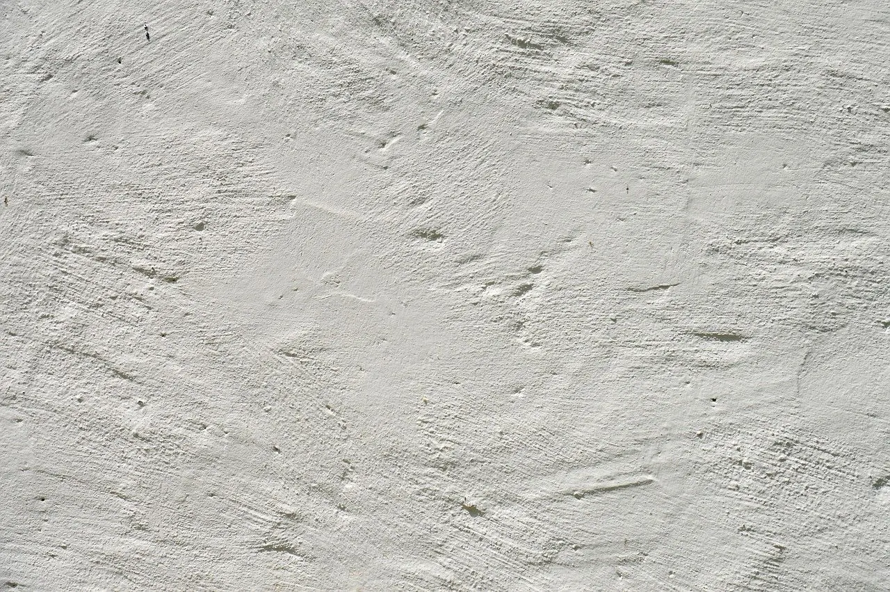 Weiß gestrichene, grob verriebene Putzfläche mit sichtbaren Kellenspuren.